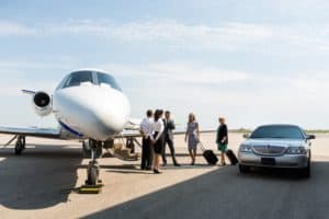 business people standing near private jet and limo